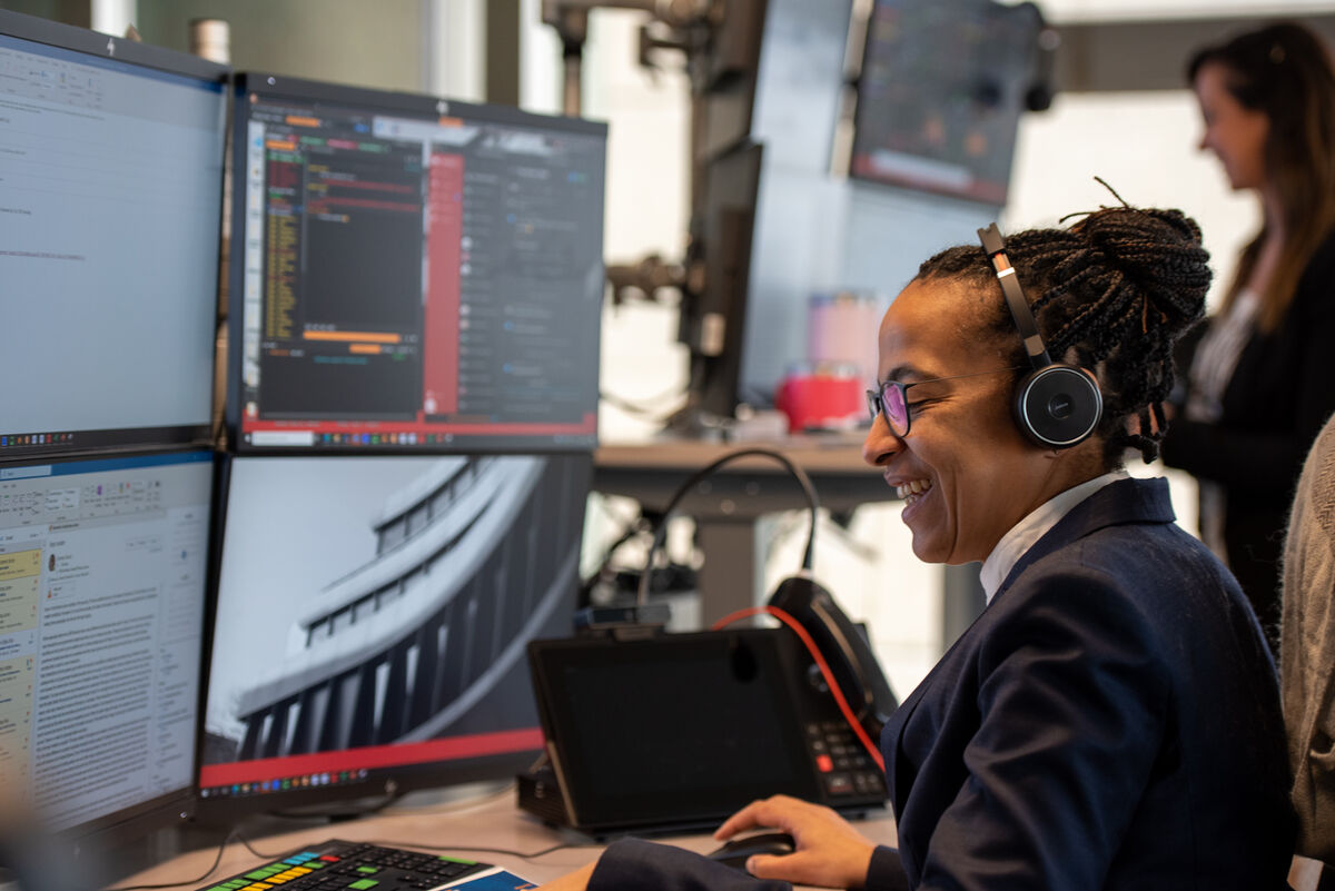 Smiling woman in front of banking terminal screens