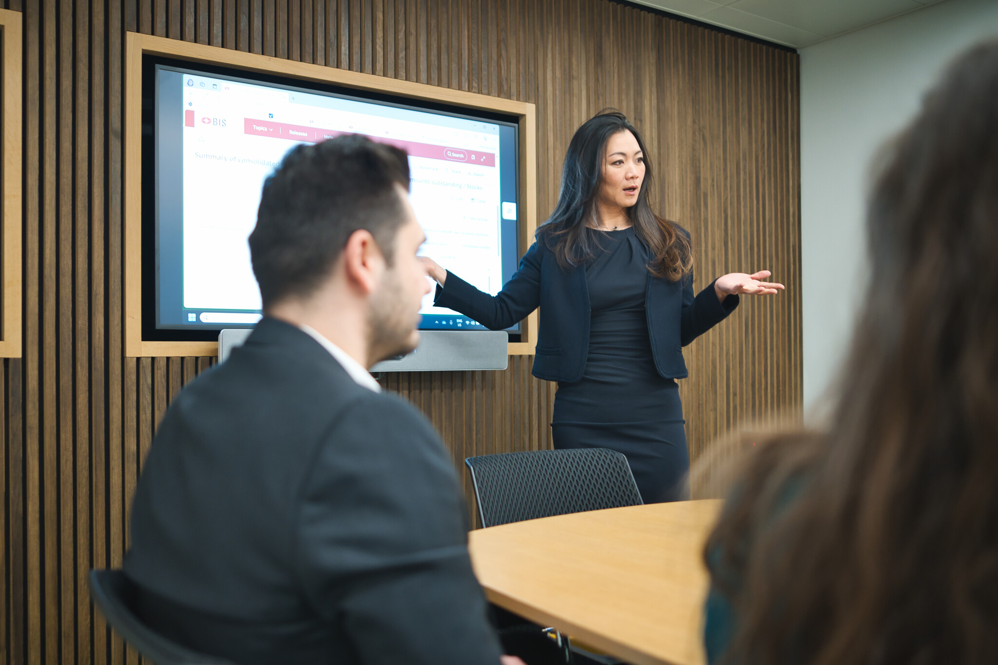 Woman talking in front of a screen while a group of people listens