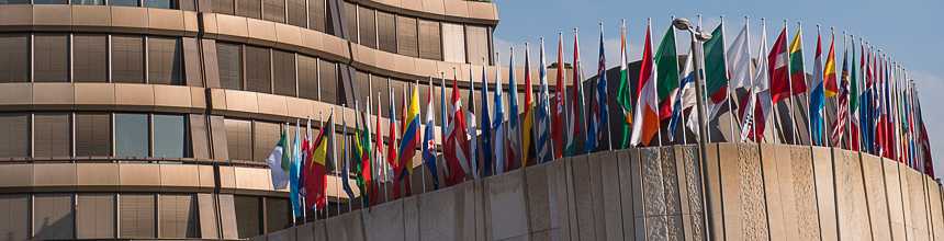 Horizontal image of the BIS headquarter building in Basel from the outside with all the country flags set up