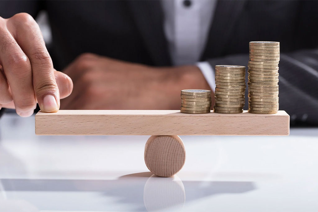 Person balancing coins on a wooden plank