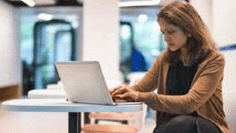 Person using a laptop while sitting on a desk