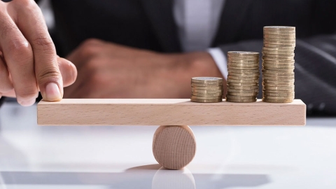 Person balancing coins on a wooden plank