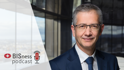 Pablo Hernandez de Cos in a suit and glasses standing in an office setting with large windows in the background. The text 'BISness podcast' with a red microphone icon is displayed on the left, representing a podcast theme.
